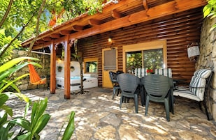 Una cabaña de madera con un patio de piedra, un jacuzzi y mobiliario exterior.