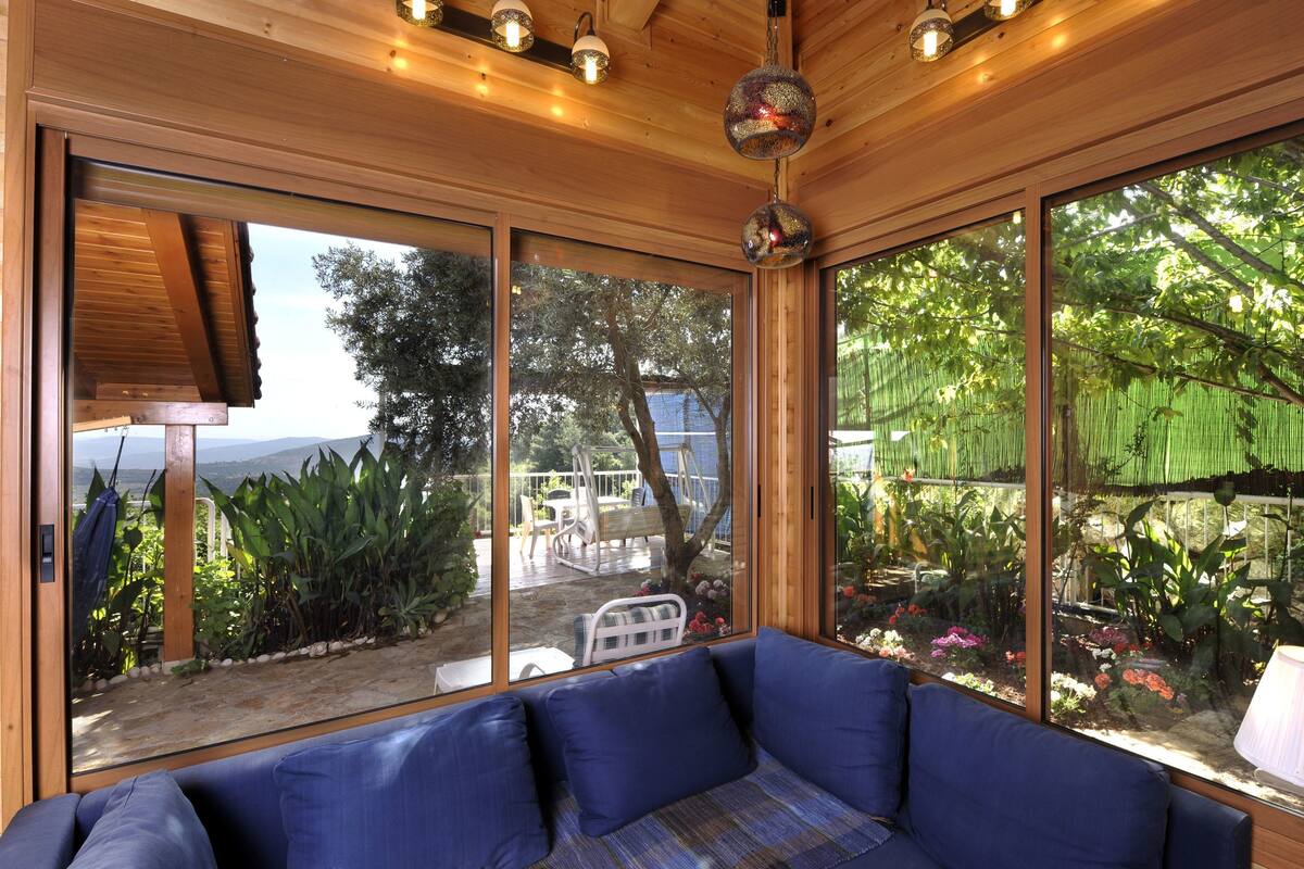 A modern room with large windows, a blue sofa, and a hanging light fixture.
