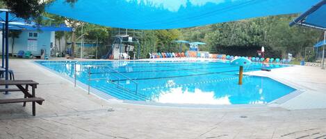 A swimming pool with multiple lanes, surrounded by lounge chairs and umbrellas.