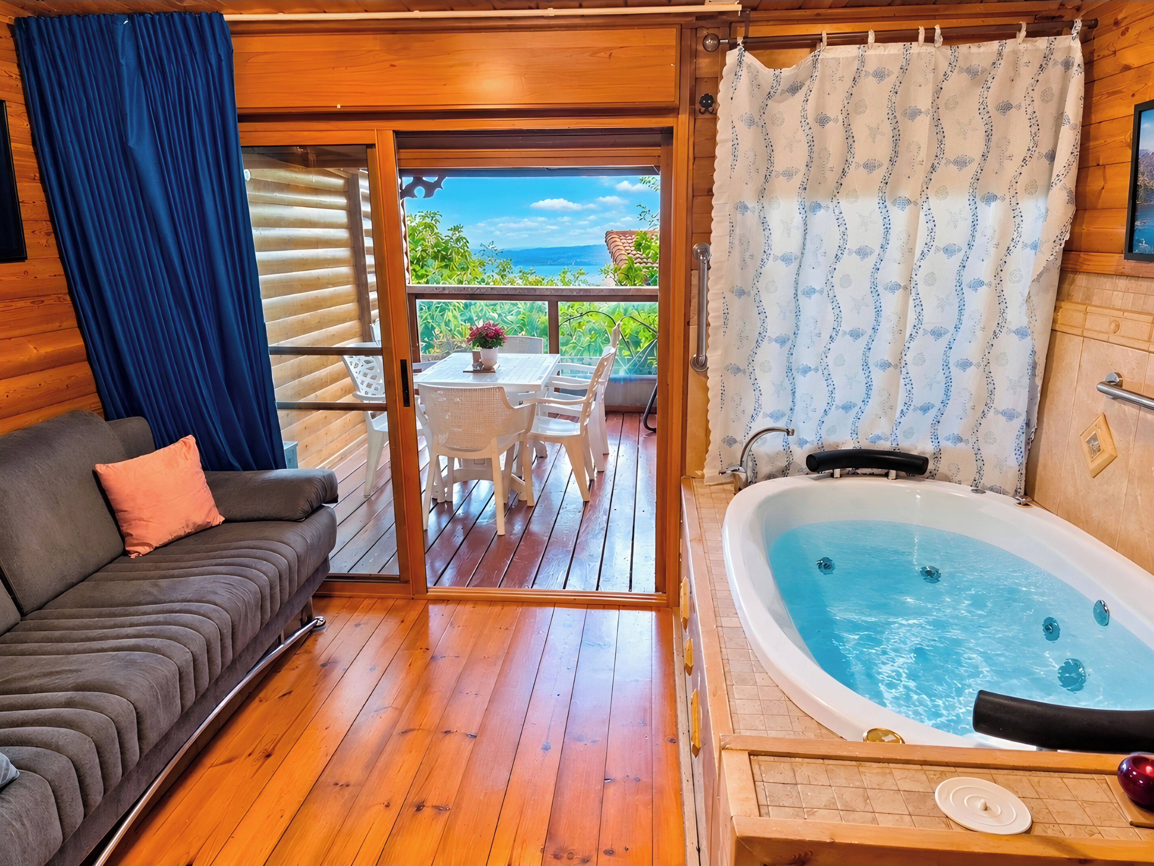 Terraza de madera con sofá, jacuzzi y vistas al exterior.