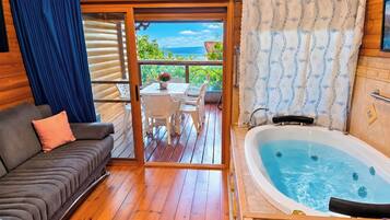 Terraza de madera con sofá, jacuzzi y vistas al exterior.