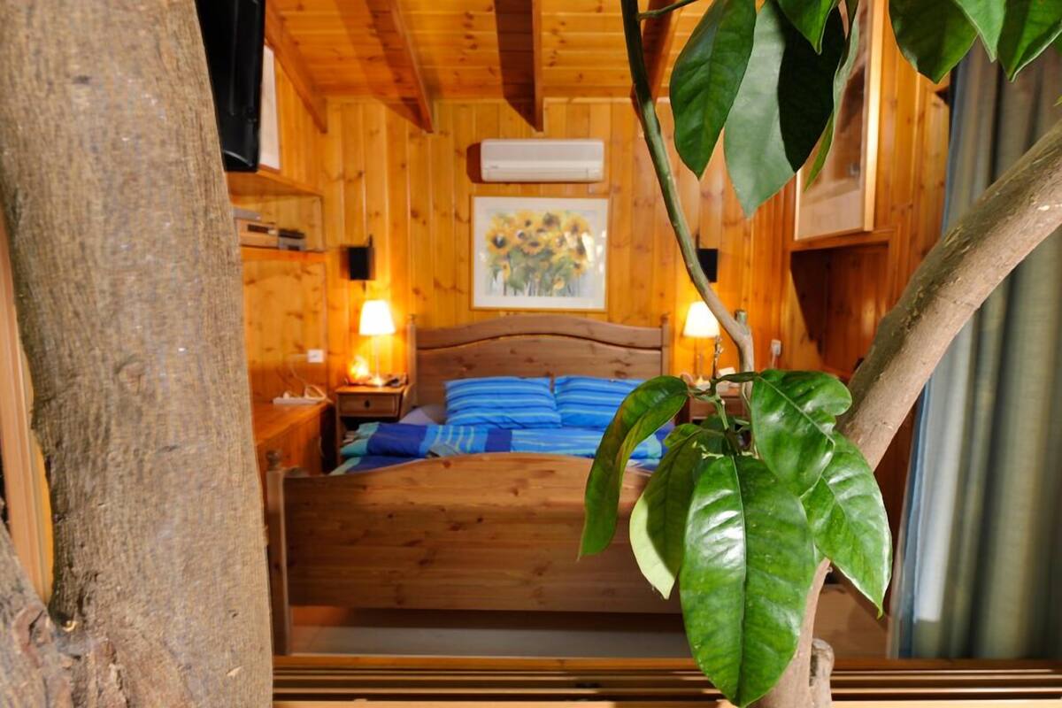 A wooden cabin room with a bed, nightstands, and a painting on the wall.