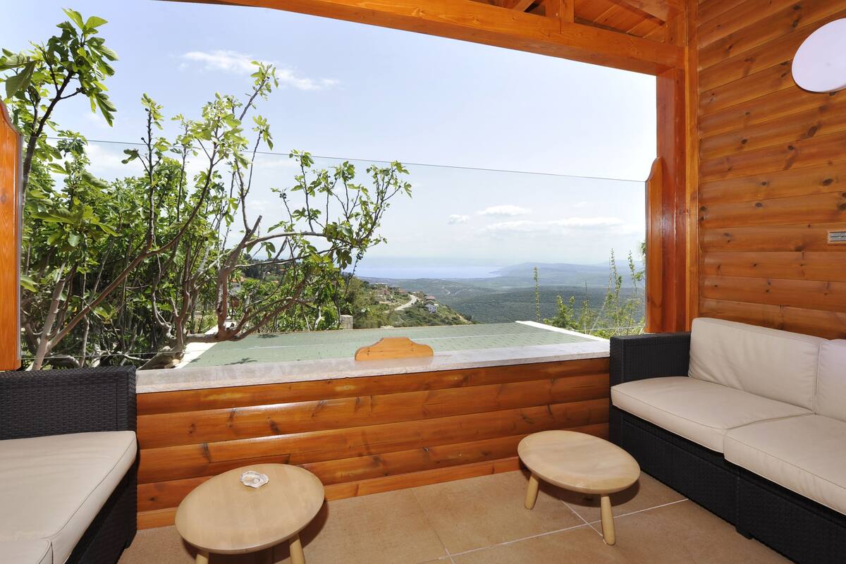 A wooden cabin with a balcony overlooking a scenic landscape.