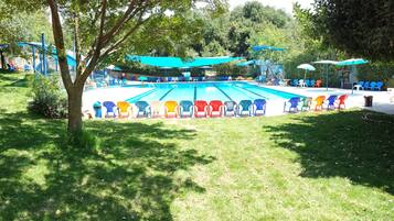 Relax by the pool surrounded by lush greenery and shaded by a canopy.