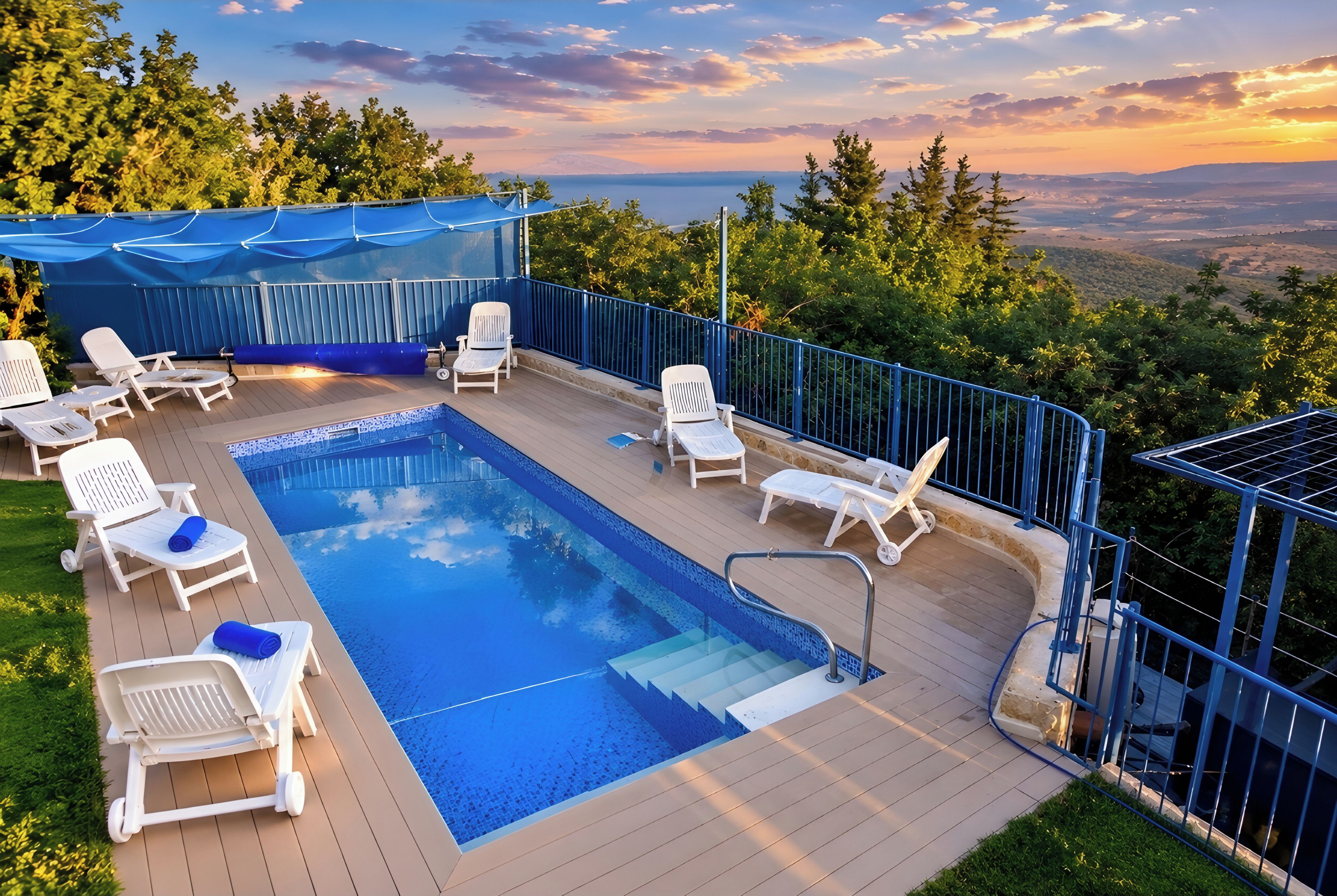 A swimming pool with lounge chairs and a blue canopy, surrounded by a deck and a scenic view.