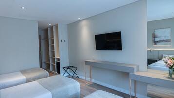 Een moderne hotelkamer met twee enkele bedden, een aan de muur bevestigde televisie, een klein tafeltje en een zithoek.