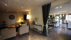 A spacious living area with a sofa set, a console table with decorative items, and a large window with curtains.