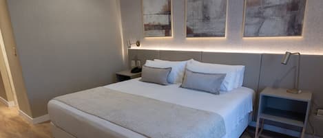 A modern bedroom with a large bed, bedside tables, and abstract wall art.