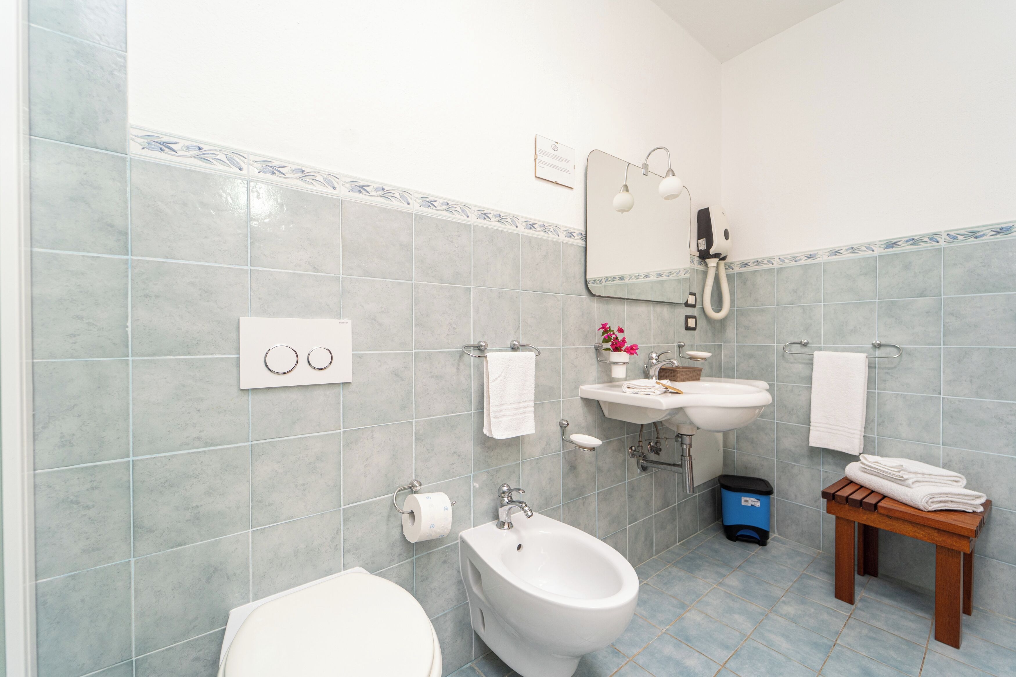 Un baño con inodoro, bidé, lavabo y espejo.