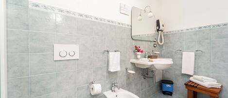 Un baño con inodoro, bidé, lavabo y espejo.