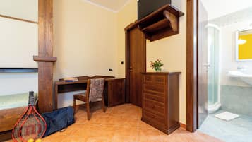 Une pièce avec un bureau en bois, une chaise et un petit meuble. On peut voir une raquette de tennis et des balles sur le sol.