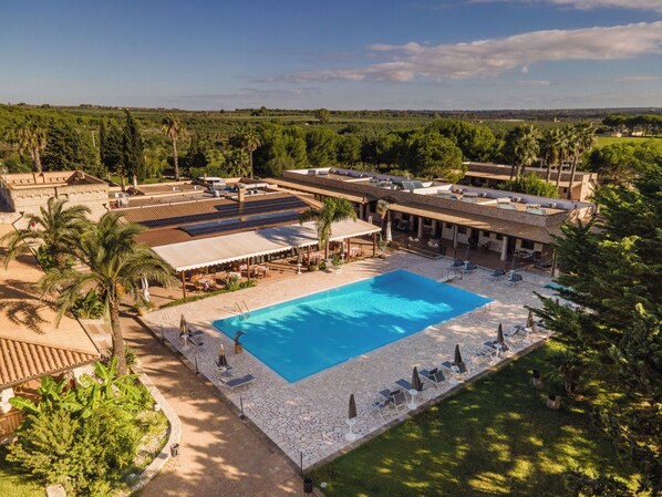 A resort with a large swimming pool, outdoor seating, and a view of the surrounding landscape. - Hotel Masseria Le Pajare (Presicce-Acquarica)