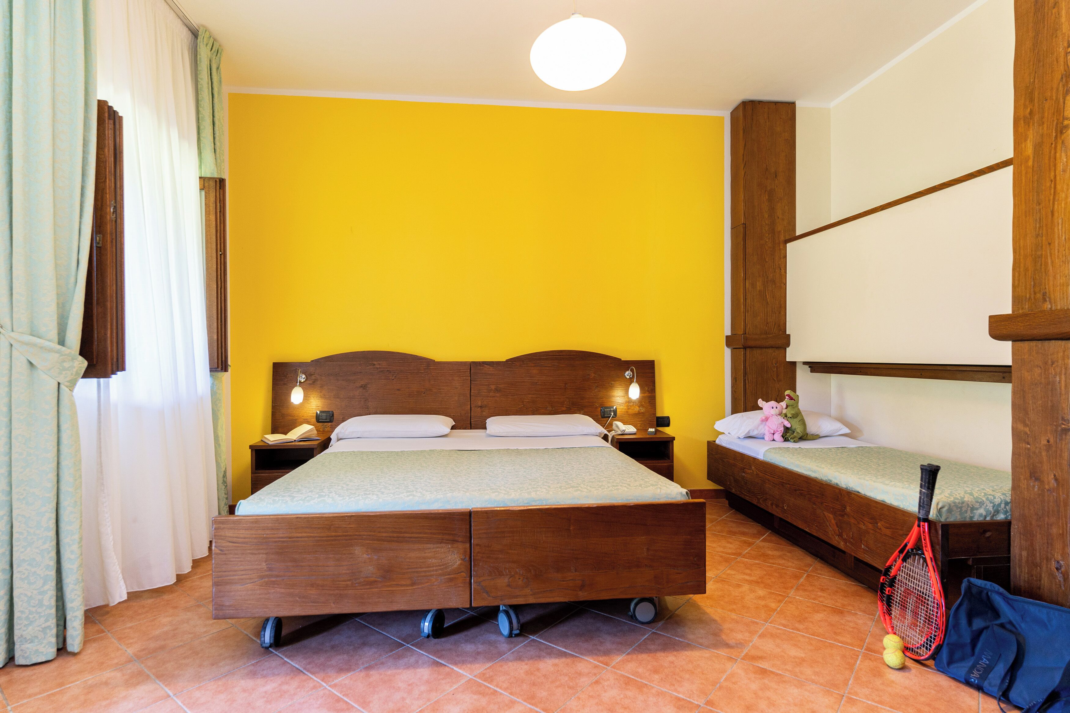 Ein Zimmer mit einem hölzernen Bett, einem kleinen Nachttisch und einem Schlafstockbett.