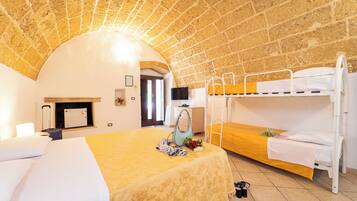 A room with a brick ceiling, a bunk bed, a single bed, a desk, and a TV.