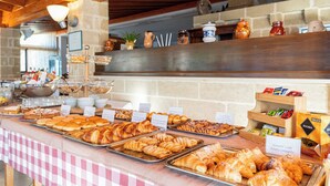 A buffet with various pastries and baked goods, including croissants and muffins, displayed on trays with labels. - Hotel Masseria Le Pajare (Presicce-Acquarica)