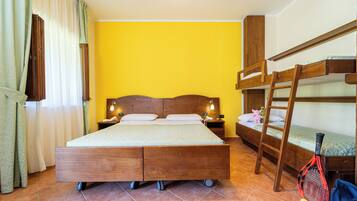 A room with a large bed, bunk beds, a ladder, and a tennis racket.