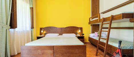 A room with a large bed, bunk beds, a ladder, and a tennis racket.