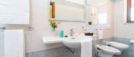 A modern bathroom with a sink, mirror, towel rack, bidet, and toilet.
