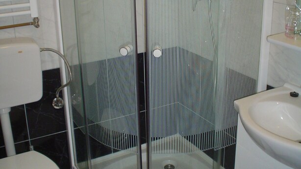 Un baño con ducha de vidrio, inodoro y lavamanos.