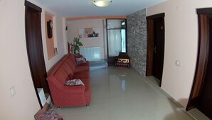 Un pasillo con un sofá rojo, una pequeña mesa con una lámpara y una pared de piedra.