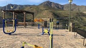 An outdoor exercise area with equipment, a wooden shelter, and a stone wall. - Hostal La Escapada (Uleila del Campo)