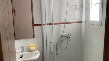 A small, modern bathroom with a glass-enclosed shower, a white sink, and a toilet.