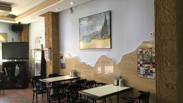 Un restaurante con mesas y sillas, un cuadro en la pared y un televisor al fondo.