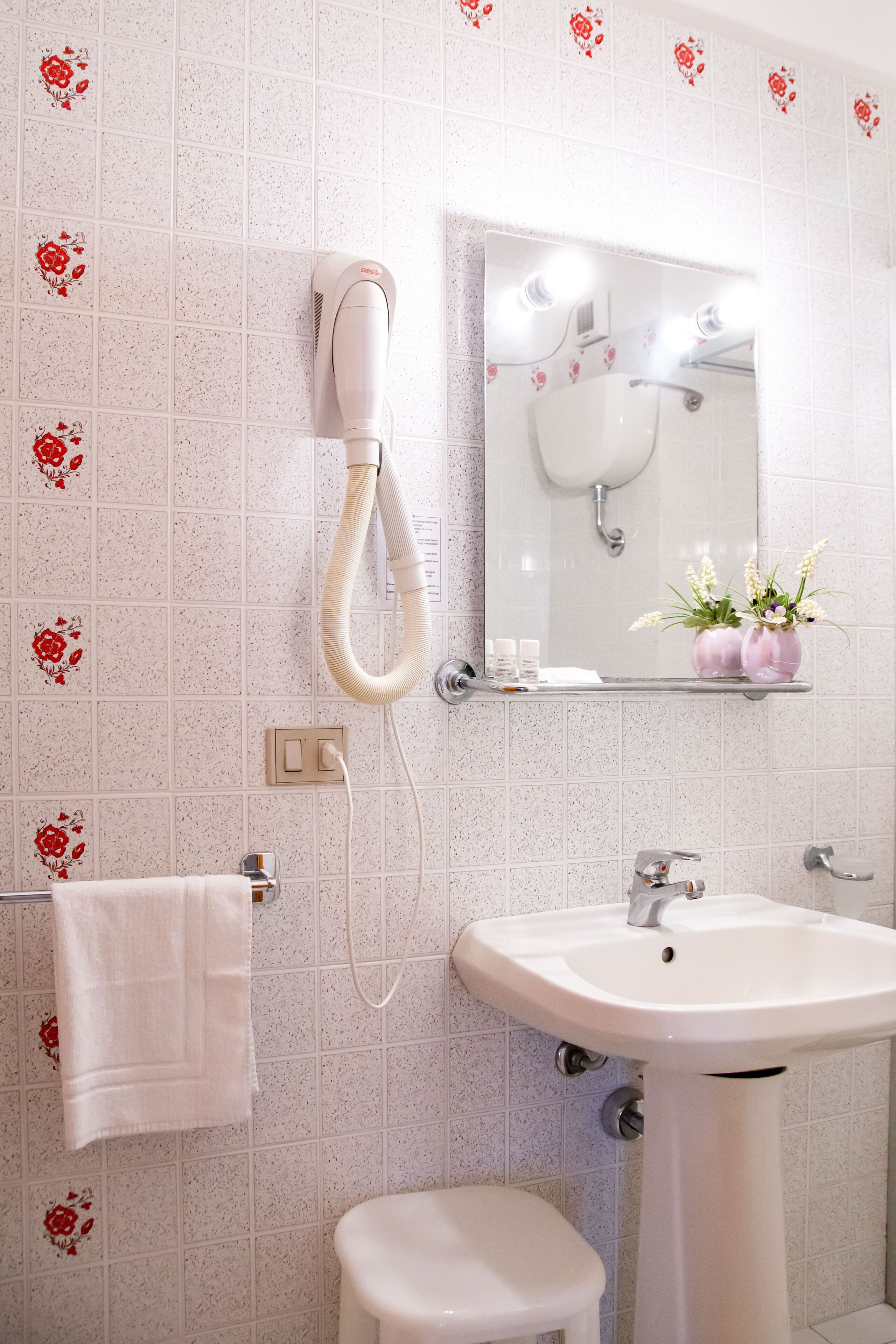 A bathroom with a white sink, a mirror, a hairdryer, and a towel rack.