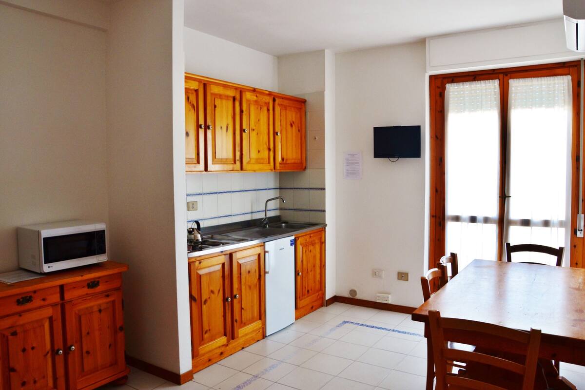 A kitchen with wooden cabinets, a microwave, a dishwasher, and a dining table with chairs.