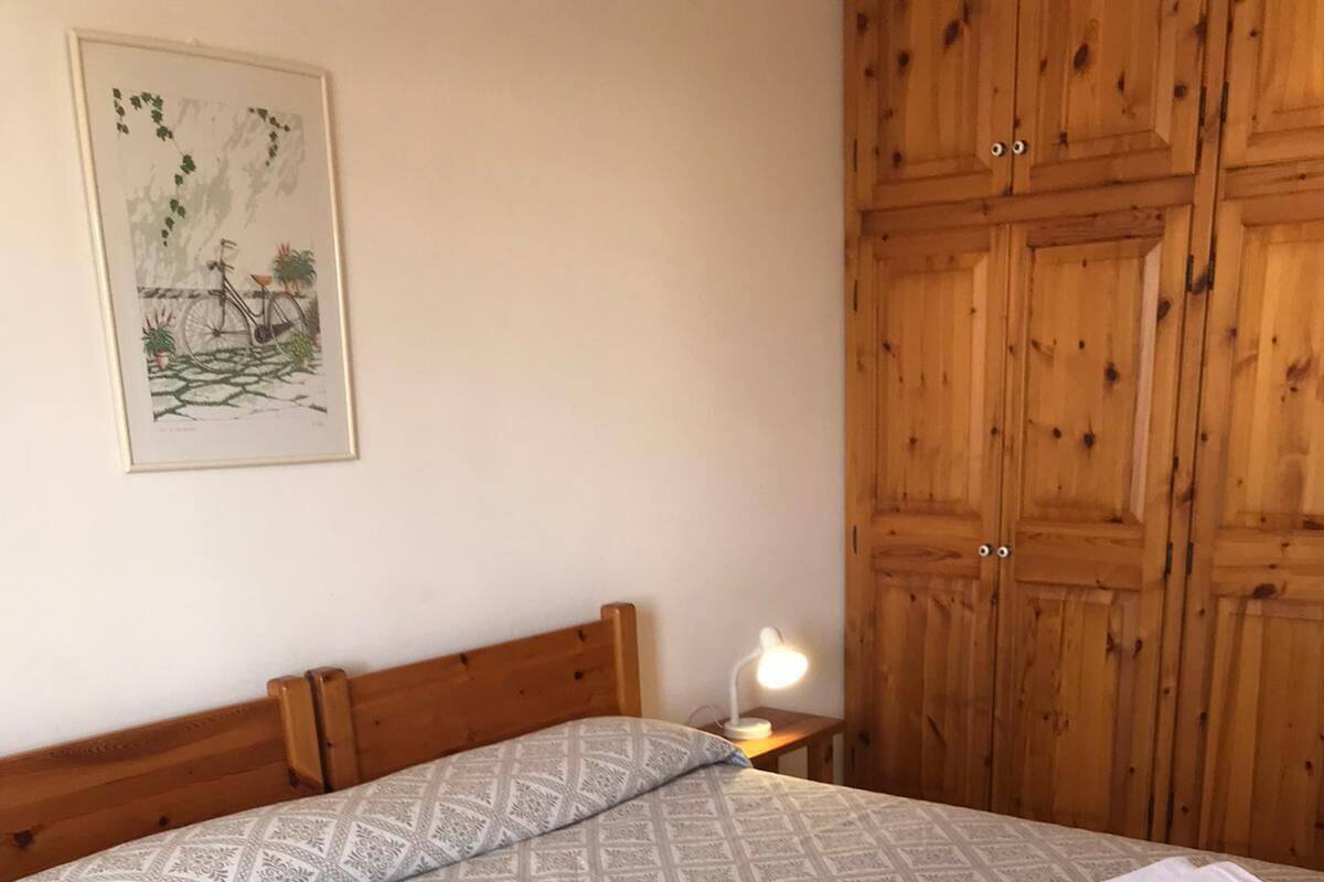 A neatly made bed with a patterned bedspread, a bedside lamp, and towels on the bed.
