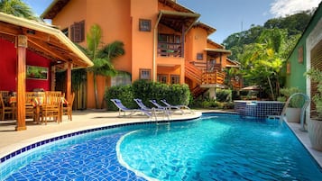 Relax by the pool surrounded by lush tropical plants and palm trees.