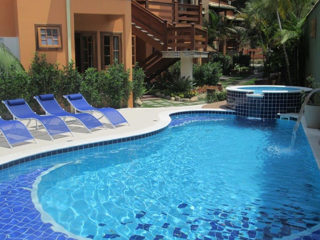 Piscina com azulejos azuis, espreguiçadeiras e uma banheira de hidromassagem.
