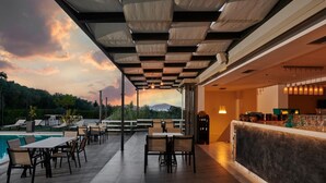 An outdoor dining area with a pool, tables, and chairs, overlooking a scenic landscape with mountains. - Altamar Hotel (Istiaia-Aidipsos)
