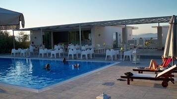 Relax by the serene pool surrounded by lush greenery and a scenic view.