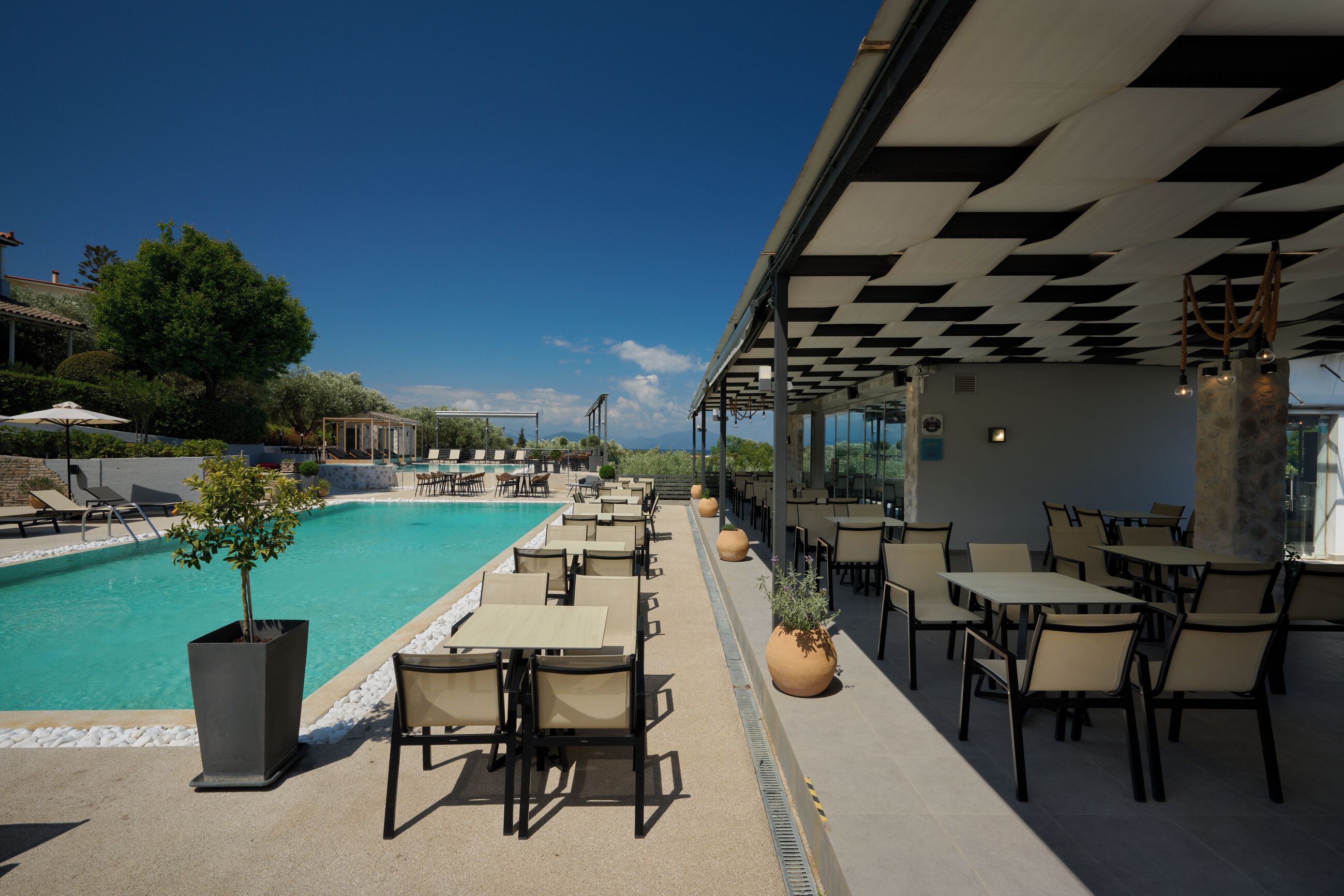 A poolside area with lounge chairs, tables, and potted plants.