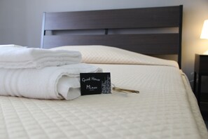 A neatly made bed with a folded white towel and a black sign that reads "Guest House Minas." - Guest House Minas (Milan)