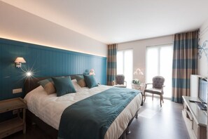 A modern hotel room with a large bed, two chairs, a TV, and a desk. - B&B Riche Terre (Damme)