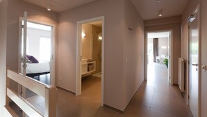 A modern hotel room with a large bed, a bathroom, and a hallway leading to other rooms. - B&B Riche Terre (Damme)