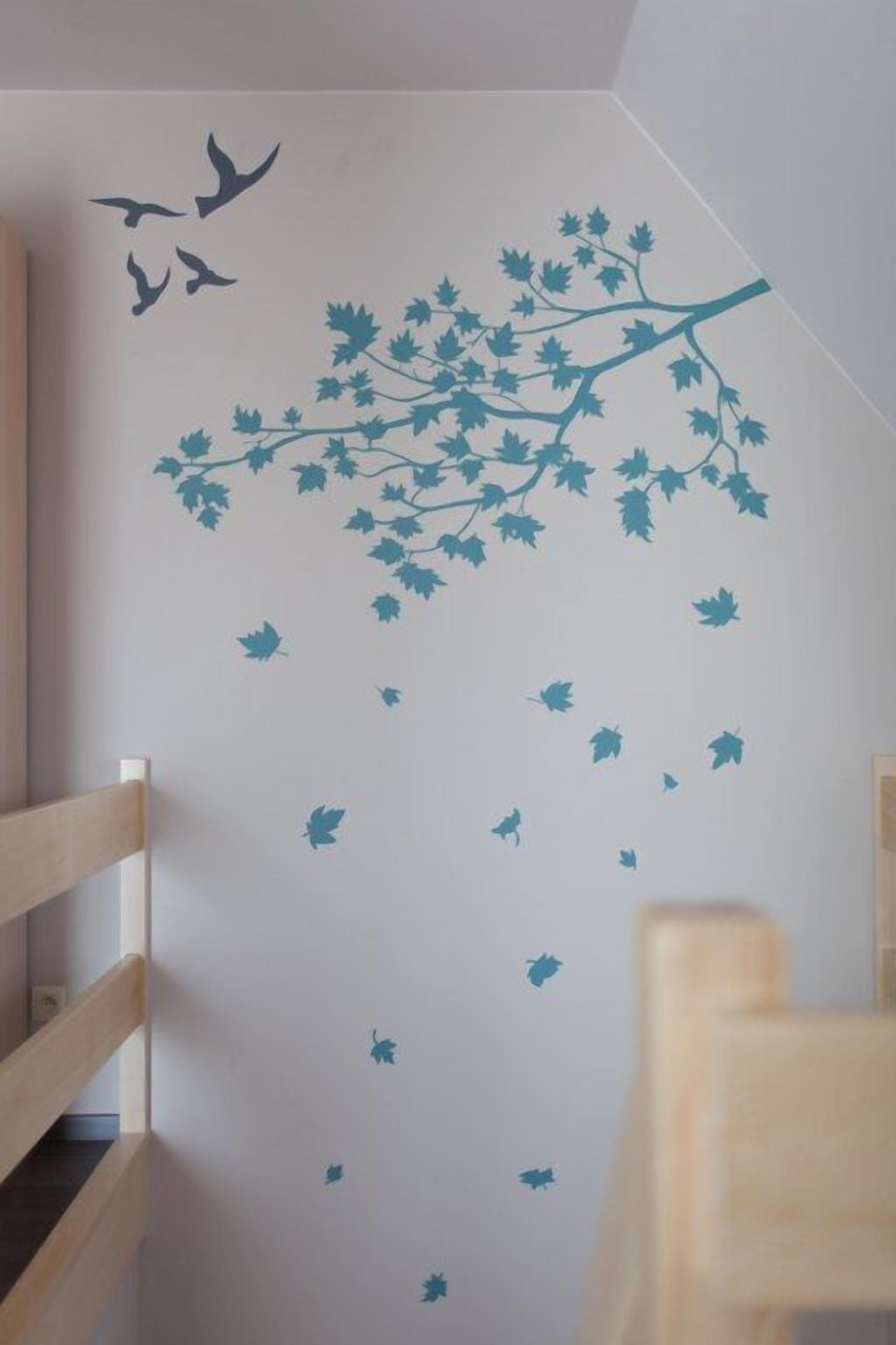 A room with a white wall featuring a tree branch and leaves decal, a wooden chair, and a wooden bench.