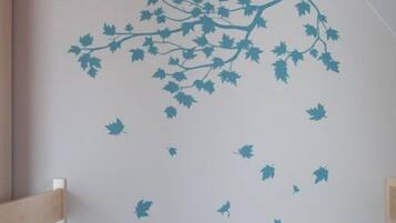 A room with a white wall featuring a tree branch and leaves decal, a wooden chair, and a wooden bench.