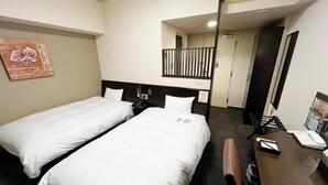 Quarto de hotel com duas camas de solteiro, uma escrivaninha com telefone e um espelho.
