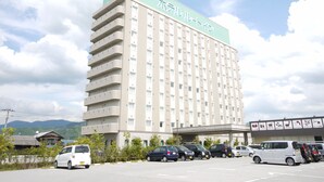 Hotel de vários andares com fachada plana e estacionamento em frente.