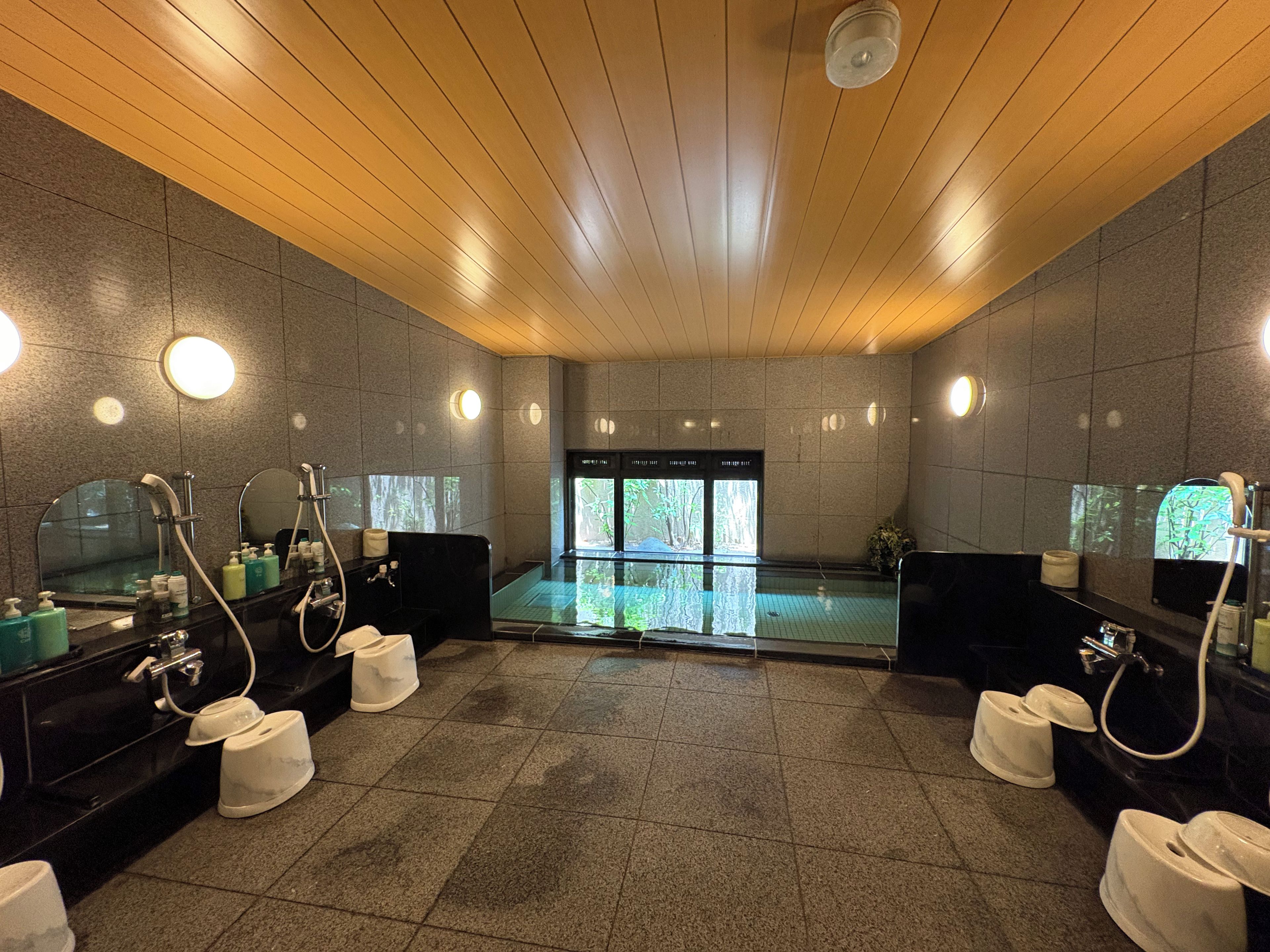 A modern bathroom with multiple sinks, mirrors, and a shower area.