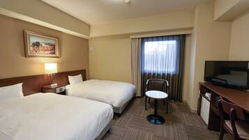 Une chambre d’hôtel avec deux lits, un bureau avec une télévision, une chaise, une lampe et un tableau au mur.