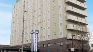 A multi-story hotel with a green roof and a sign indicating it is a hotel.