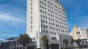A multi-story hotel with a modern design, featuring a prominent logo at the top. - Hotel Route Inn Niihama (Niihama)