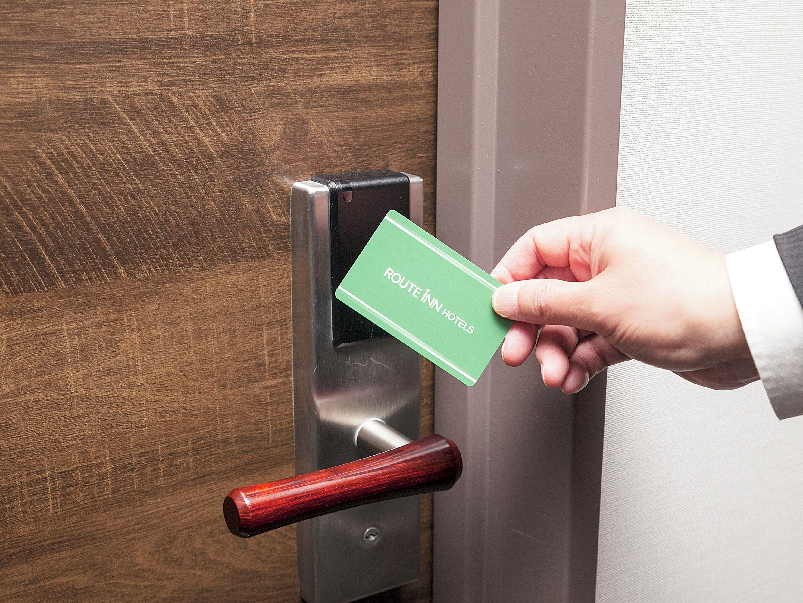 Une main insère une carte verte dans la serrure d’une porte d’hôtel.