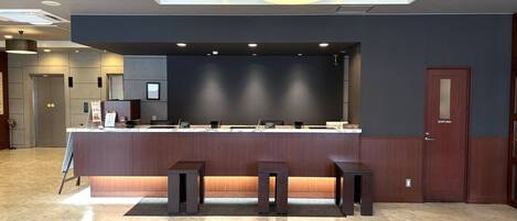 A reception area with a marble floor, a counter with a dark wood finish, and a 'staff only' door.
