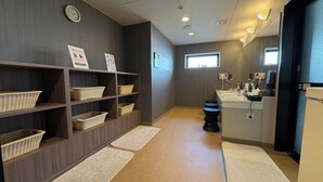 A hotel bathroom with a sink, mirror, and a window. There are baskets on shelves and a clock on the wall. - Hotel Route Inn Niihama (Niihama)