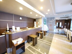 A hotel reception area with a counter, seating, and a digital screen. - Hotel Route Inn Iyo Saijo (Saijo)